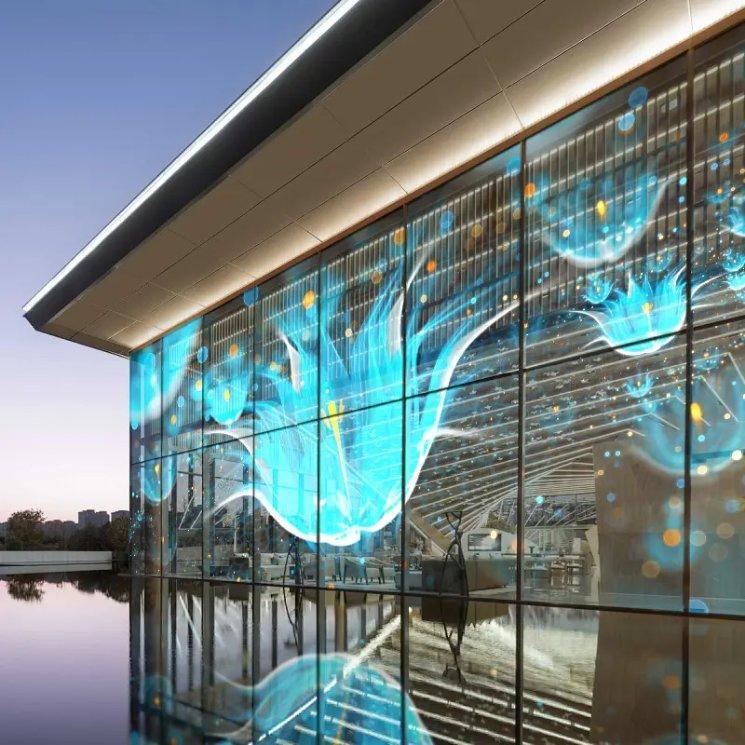 Façade vitrée équipée d'un écran LED transparent diffusant une composition lumineuse abstraite, vue de nuit
